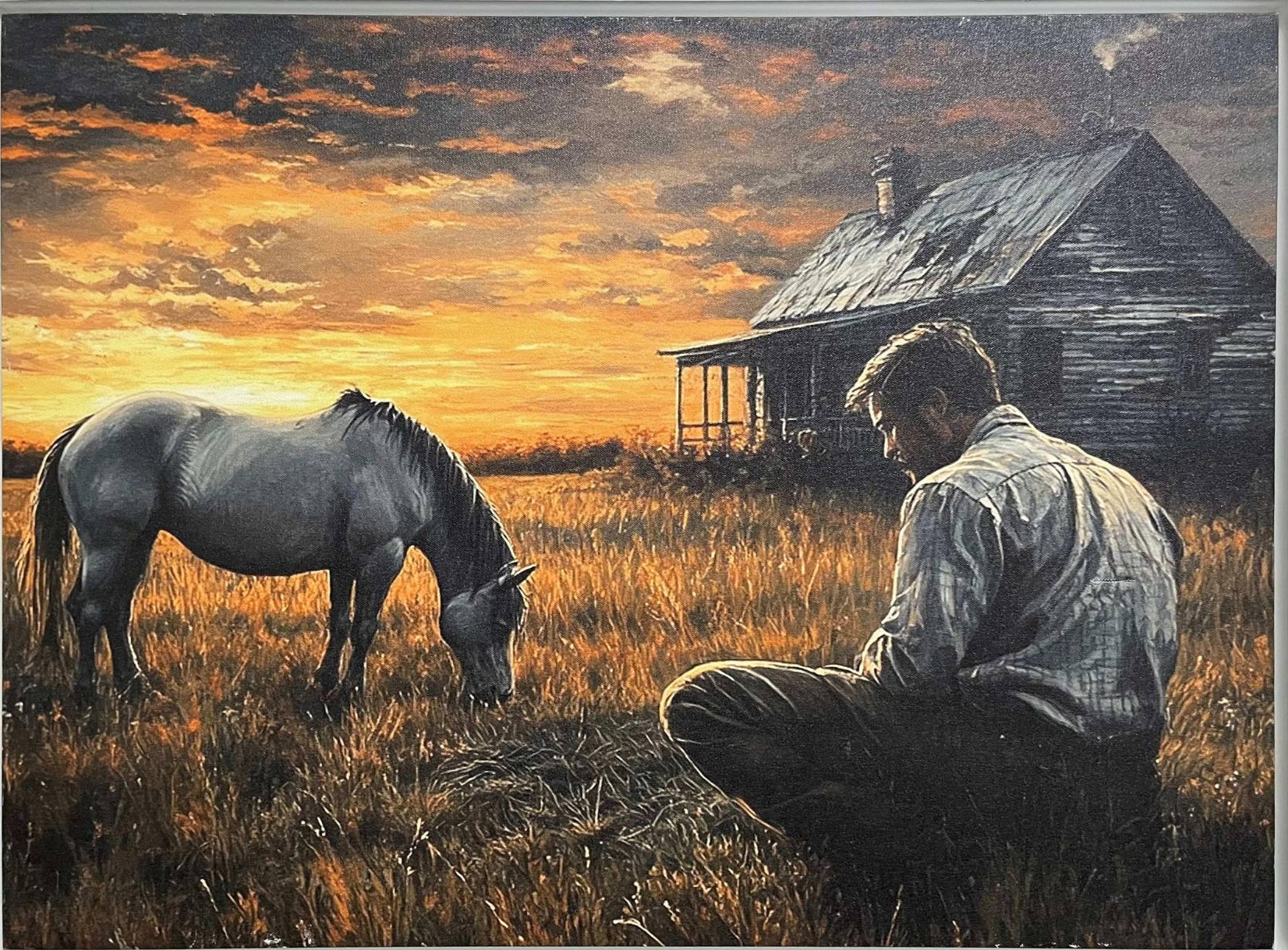 A man kneeling in a golden field at sunset, facing a grazing horse before a weathered farmhouse.